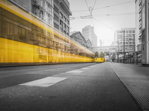 Yellow tram travels quickly through urban roads.