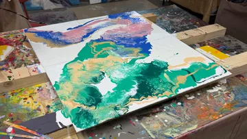 Abstraktes Gemälde auf unordentlichem Kunsttisch.