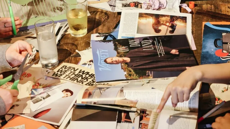 Hände schneiden Magazine auf Holztisch.