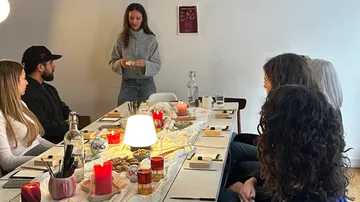 Menschen sitzen an einem kerzenbeleuchteten Tisch und hören zu.