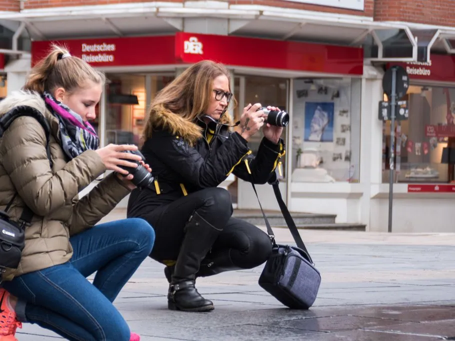 Zwei Fotografen knien und machen Fotos auf der Straße.