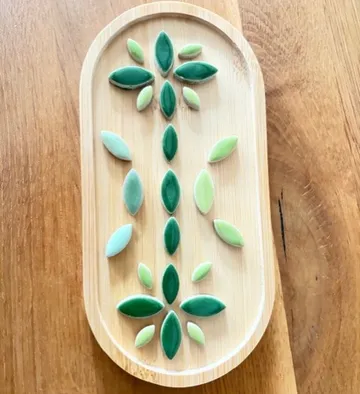 Grüne Keramikblätter auf Holztablett.