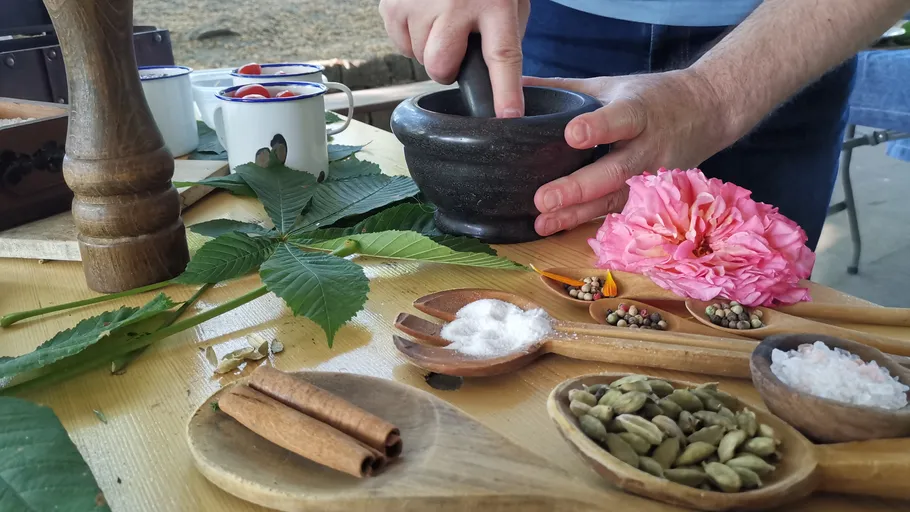 Hands using mortar and pestle, surrounded by spices.