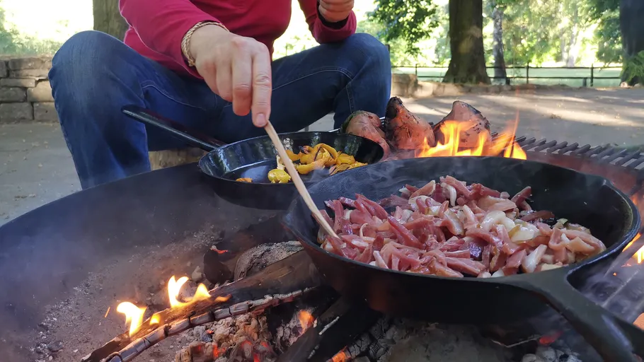 Person kocht auf offenem Feuer im Freien.