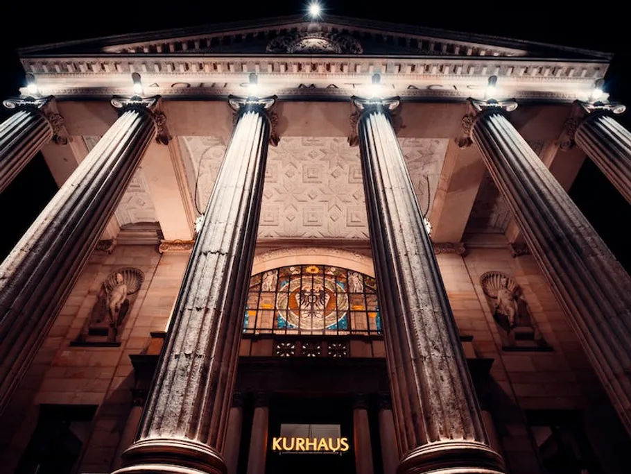Klassisches Gebäude mit Säulen, beleuchtet bei Nacht.