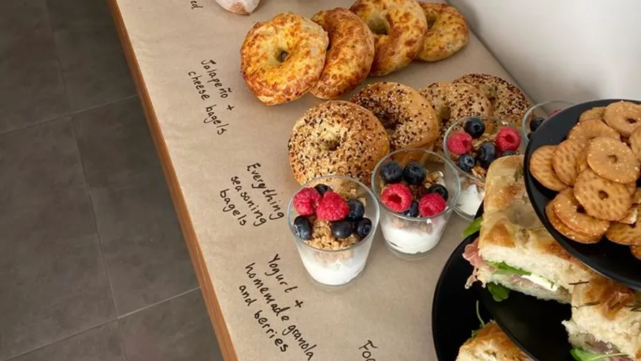 Bagels, yogurt cups, and sandwiches on table.