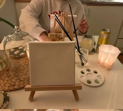 Canvas on easel, with art supplies and candle.