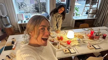Two women smiling in decorated indoor setting.