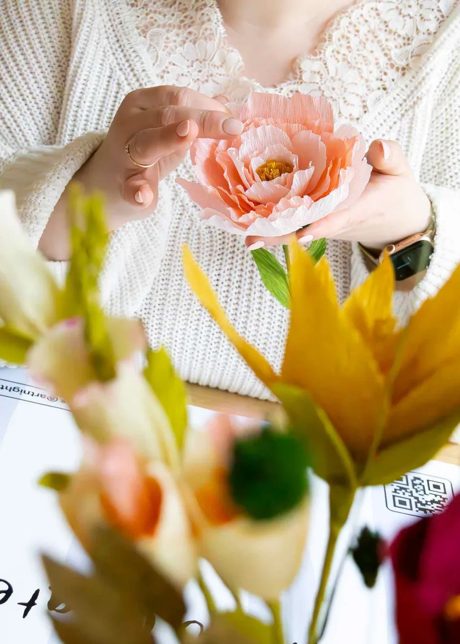 Woman holding a handmade pink flower.