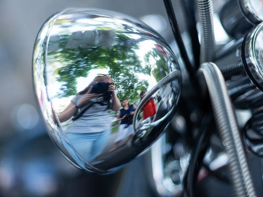 Spiegel reflektiert Fotografen und Zuschauer in grüner Umgebung.