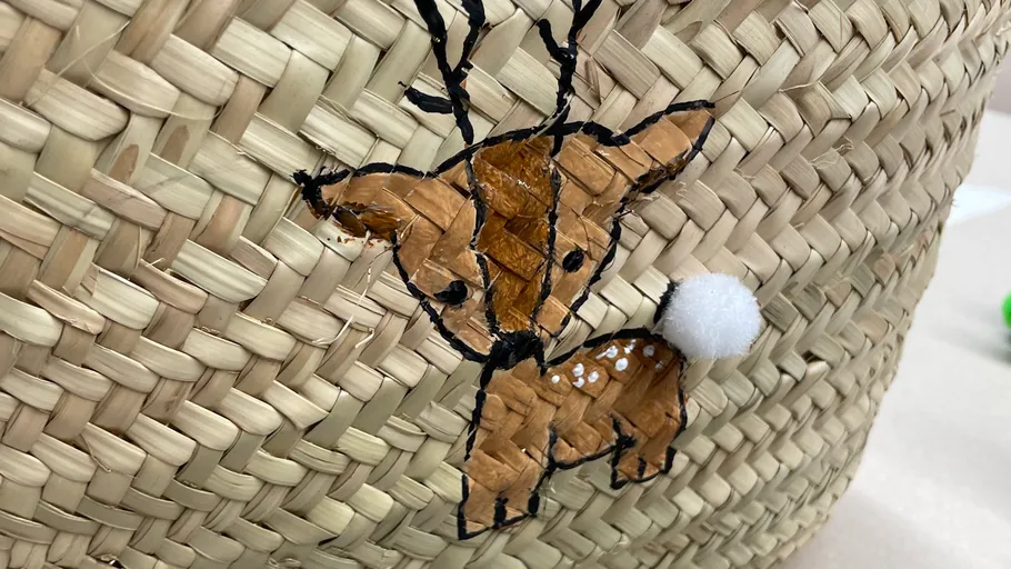 Woven basket with reindeer decoration attached.