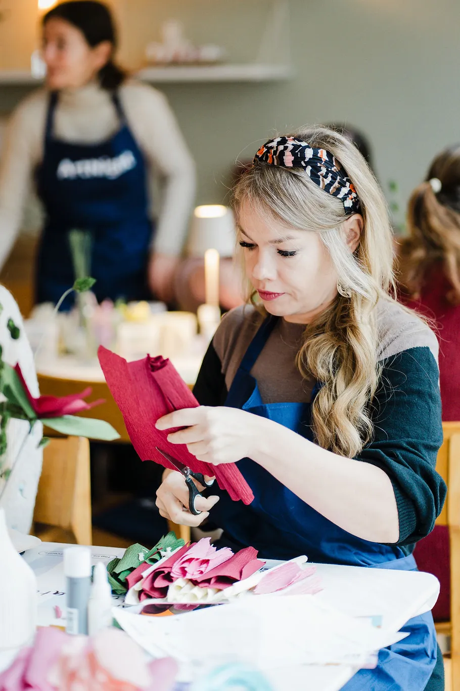 Woman cutting red paper in craft class.