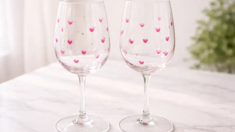 Two wine glasses with heart patterns on table.