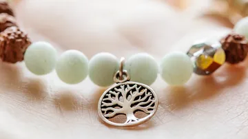 Bracelet with tree charm on hand.