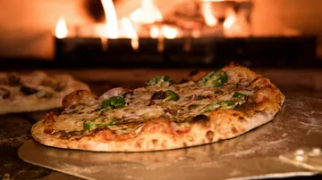 Pizza cooking in wood-fired oven.