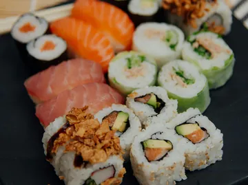 Verschiedene Sushirollen auf schwarzem Teller.