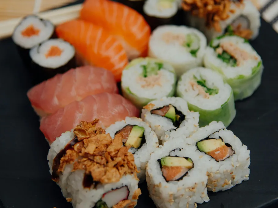 Verschiedene Sushirollen auf schwarzem Teller.