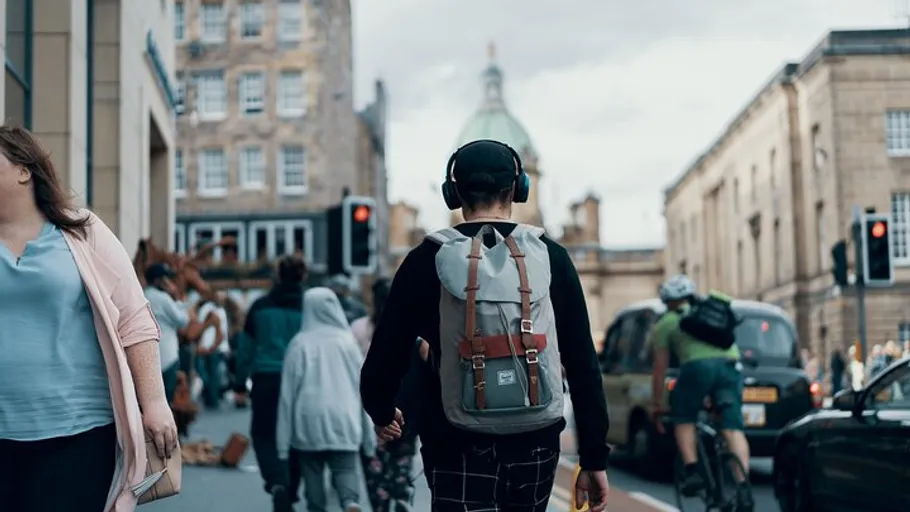 Person with backpack walking in busy city.