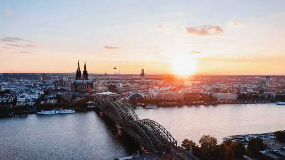 Cityscape with cathedral, bridge, river at sunset.