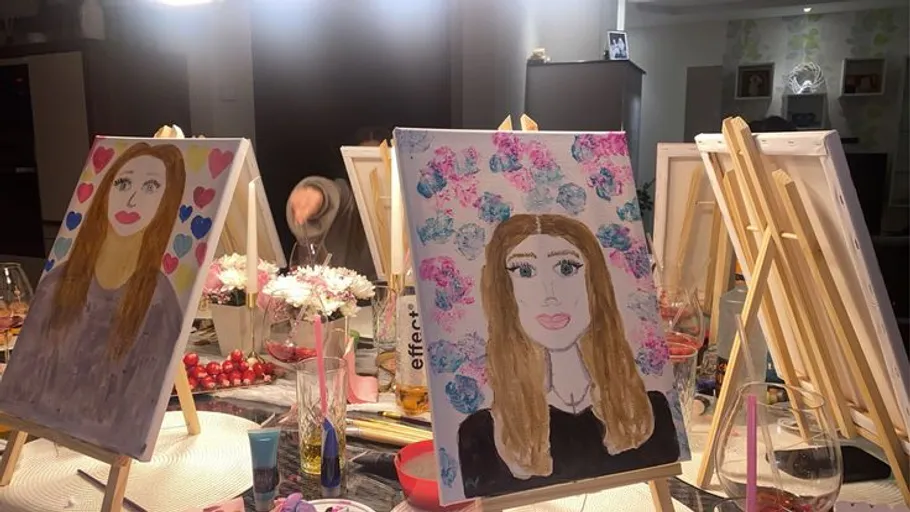 Paintings on easels in a colorful workshop.