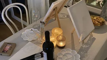 Painting setup with wine and candles.