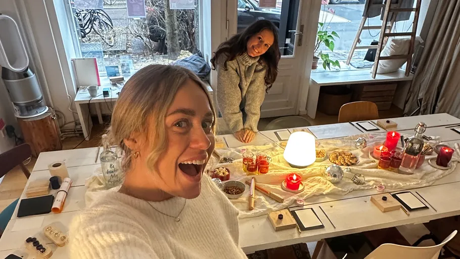 Zwei Frauen lächeln an dekoriertem Tisch drinnen.