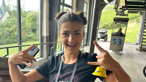 Lachende Frau gestikuliert, sitzt drinnen.