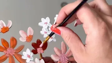 Hand painting flowers on a surface.