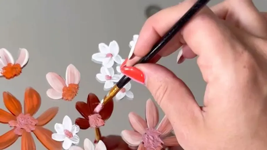 Hand painting flowers on a surface.
