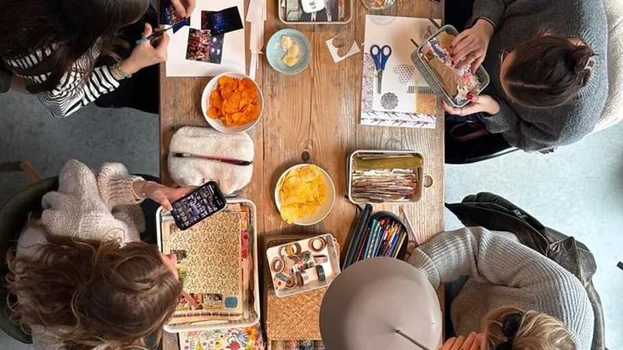 People crafting at a table with snacks.