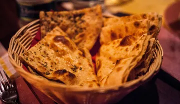 Korb mit Naan-Brot auf einem Tisch.