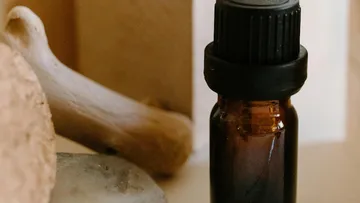 Braune Flasche mit schwarzem Verschluss, Knochen in der Nähe.