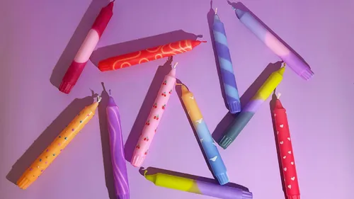 Colorful patterned candles on a purple background.