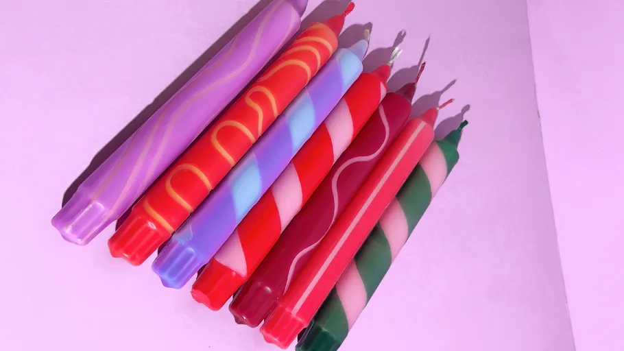 Bunte Spiralkerzen auf rosa Oberfläche.