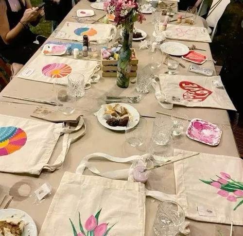 Tisch mit bemalten Taschen, Kunstbedarf und Snacks.