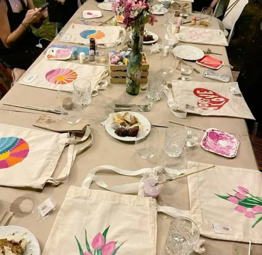 Table with painted bags, art supplies, and snacks.
