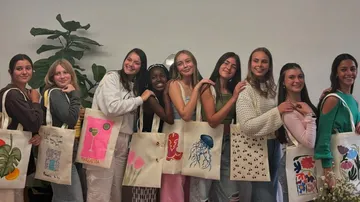 Gruppe junger Frauen mit dekorierten Tragetaschen.