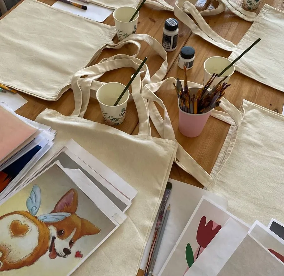 Jutetaschen, Bilder, Pinsel auf Holztisch.