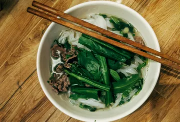 Schüssel Pho mit Stäbchen auf Holztisch.