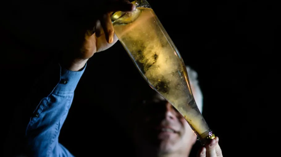 Hand holding an illuminated champagne bottle.