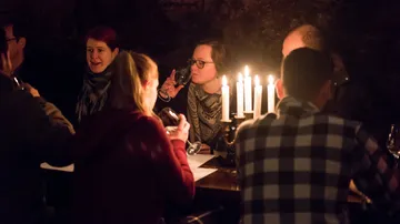 People enjoying wine around candlelit table.