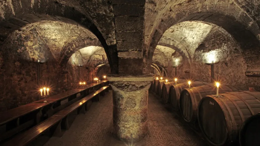 Wine barrels and candles in ancient cellar.