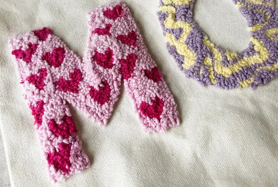 Embroidered letters M and U on fabric.