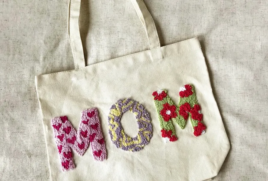 Beige tote bag with 'MOM' embroidery.