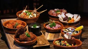 Various tapas dishes on wooden trays.