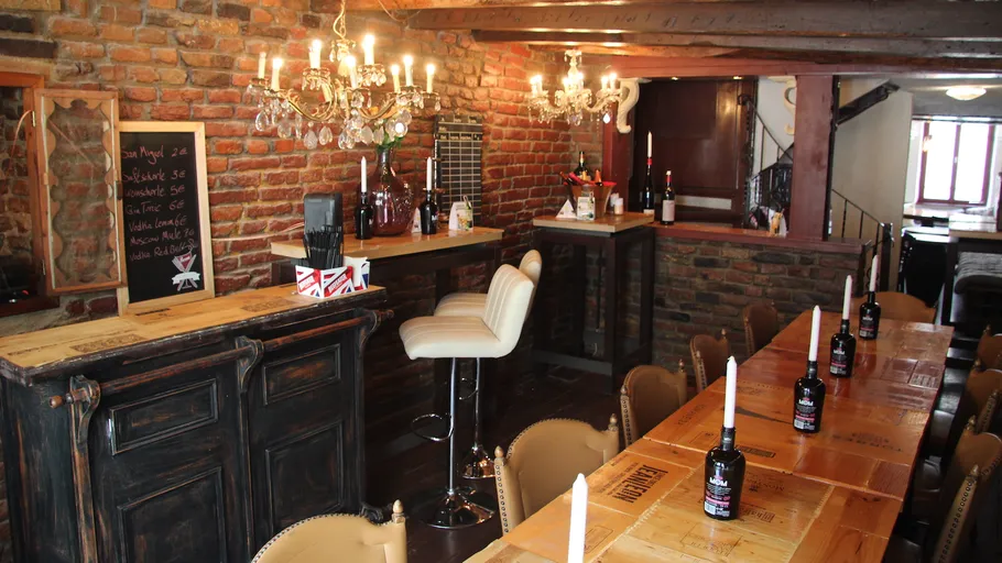 Rustikale Bar mit Holztischen und Kronleuchtern.