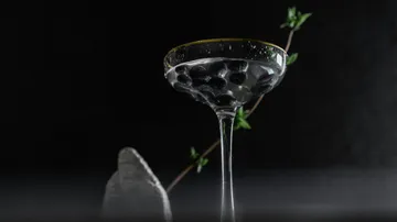 Martiniglas mit schwarzen Oliven, dunkler Hintergrund.