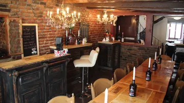 Cozy bar with brick walls and chandelier lighting.