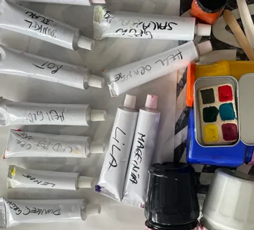 Farb-Tuben und Kunstbedarf auf Tisch.