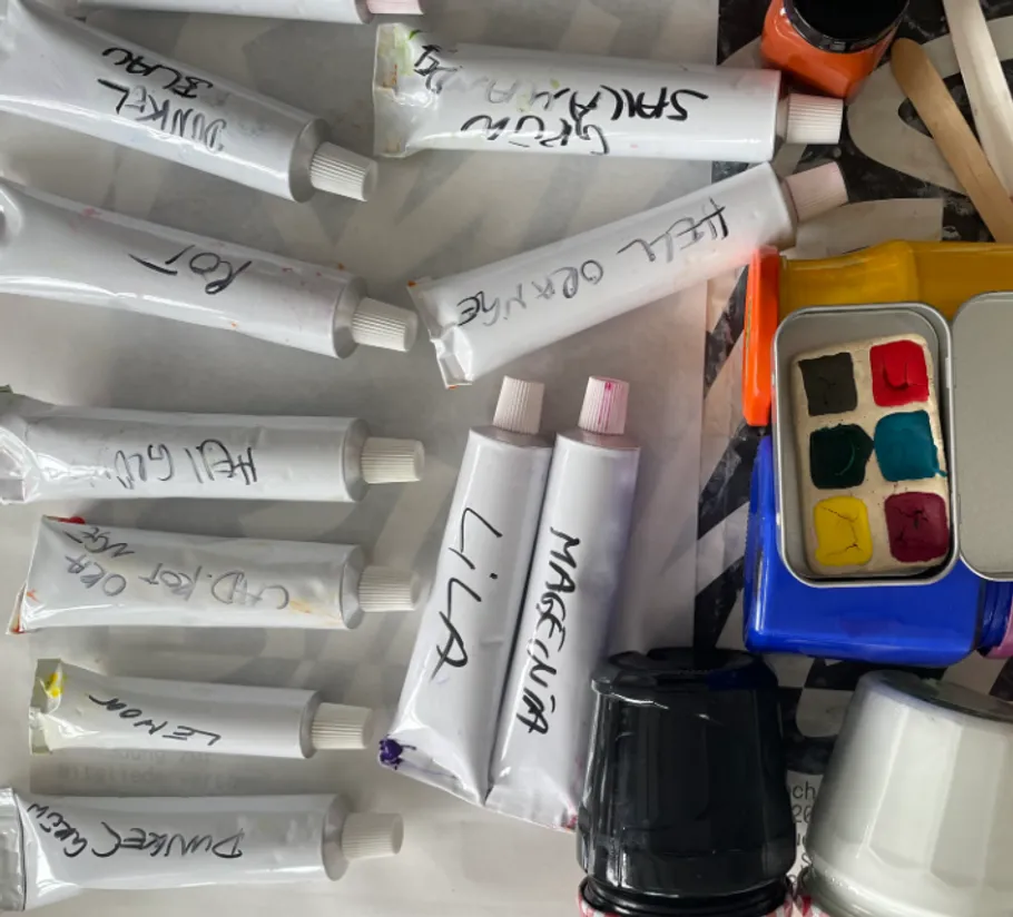 Tubes of paint and art supplies on table.